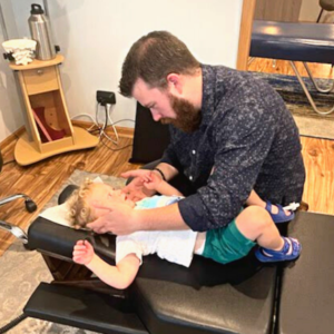 Dr. Nathan Gerowitz performing an upper cervical chiropractic adjustment on young boy